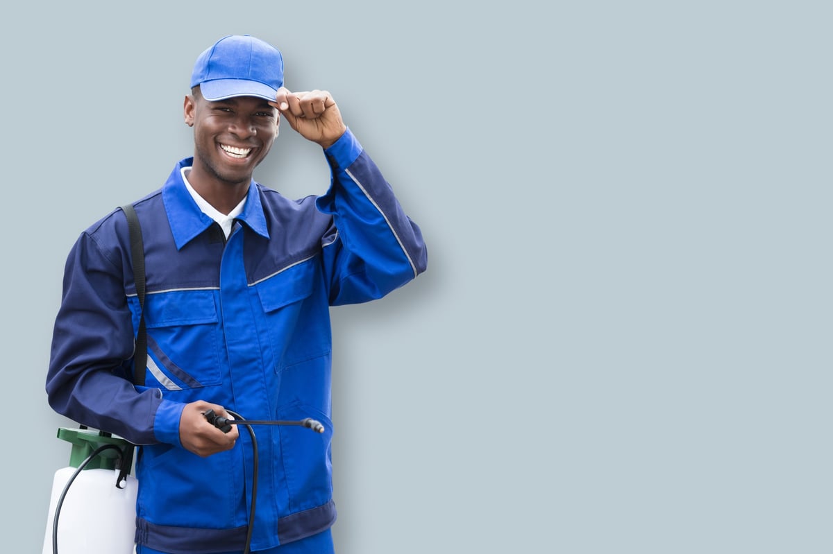 Portrait Of Young Smiling Worker With Pesticide Sprayer While Standing By Van