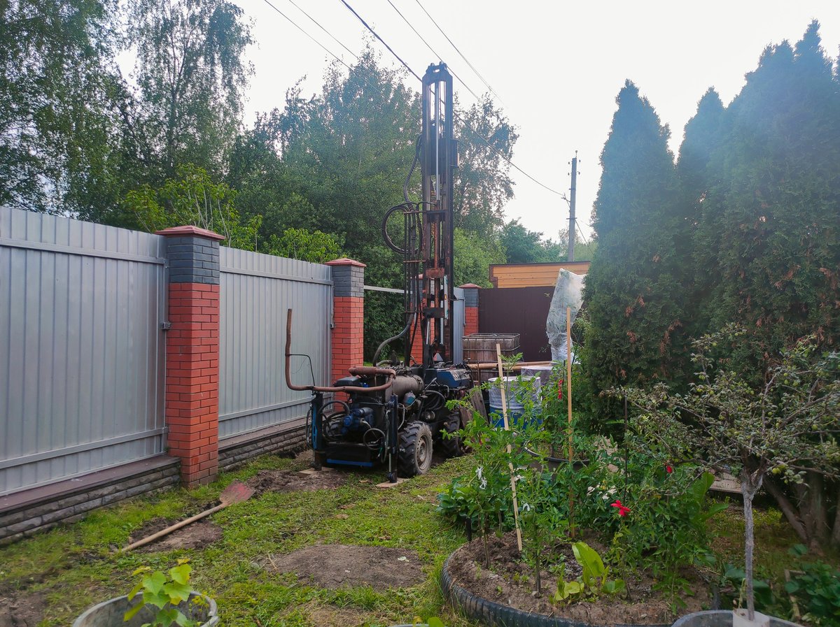 A portable drilling rig installs a new well for domestic water supply in a private garden.